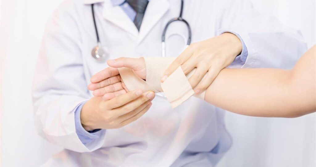 Doctor dressing patient's wound with bandage