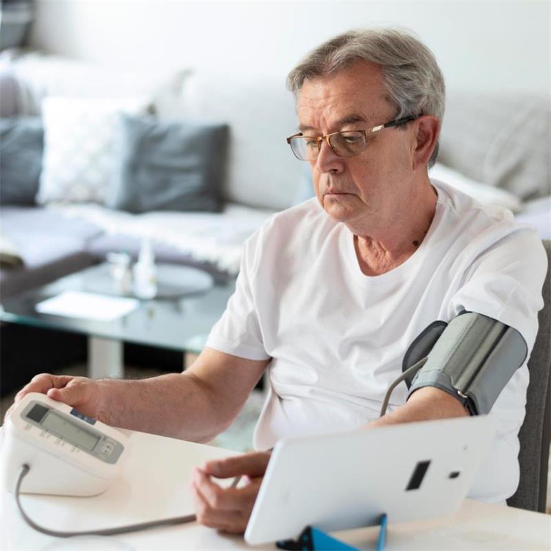 Senior man measuring blood pressure with sphygmomanometer at home