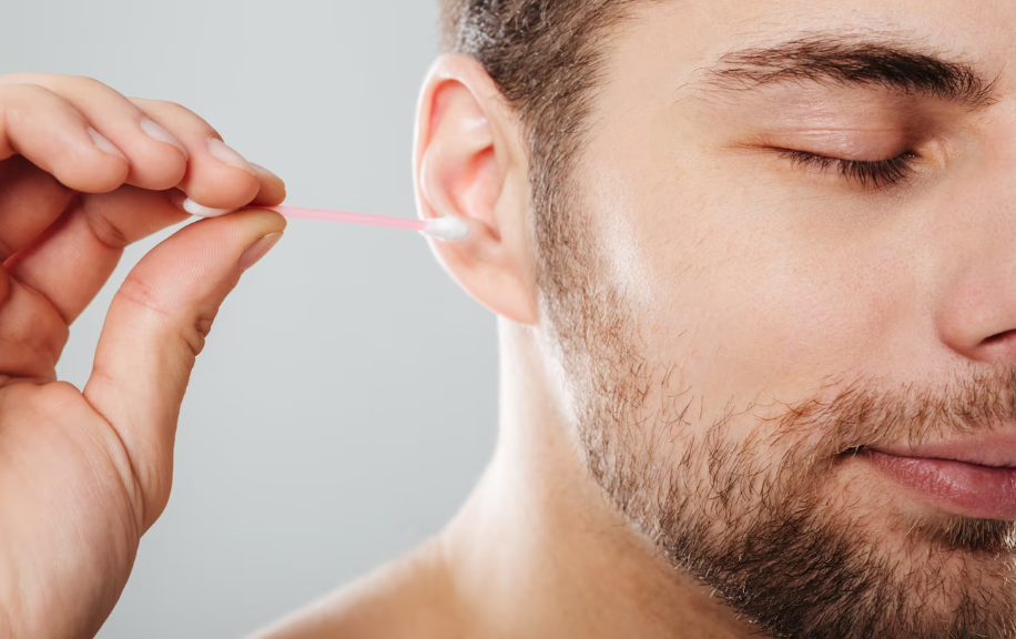 man cleaning ear with cotton bud