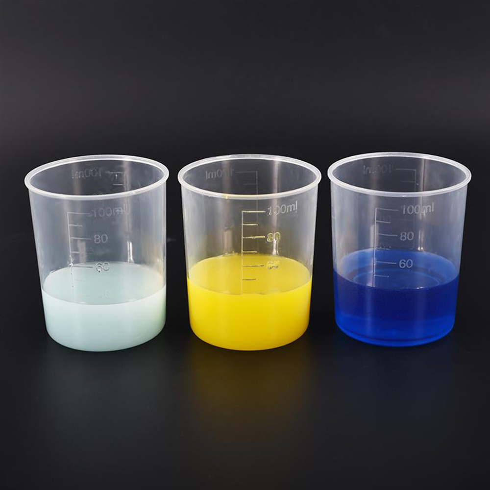 Three measuring cups filled with three colored liquids